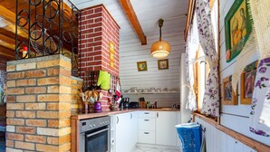 A kitchen with a brick wall, white cabinets, and a hanging pot rack. - Beautiful private villa for 6 guests with WIFI, A/C, TV, patio and pets allowed (Malý Ratmírov)