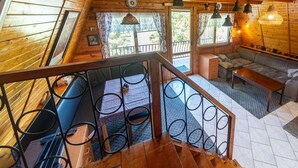 A wooden cabin interior with a staircase, seating area, and multiple hanging lights. - Beautiful private villa for 6 guests with WIFI, A/C, TV, patio and pets allowed (Malý Ratmírov)