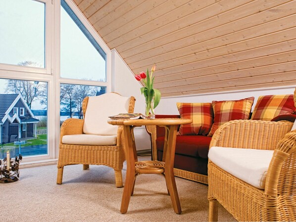 A cozy room with wicker furniture, a large window, and a view of a house.