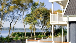 A waterfront property with a wooden deck, white railings, and a view of the lake.