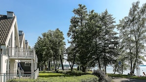 A modern building with a balcony, a paved pathway, and a lake view.