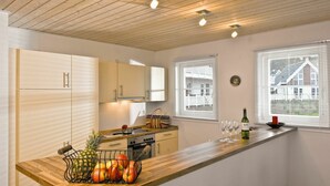 A modern kitchen with wooden cabinets, a wooden countertop, and a view of a house through the windows. - Nice apartment in villa for 6 people with hot tub, internet, TV, terrace and pets allowed (Fürstenwalde)