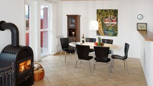 A modern kitchen with a built-in wood stove, a dining table with chairs, and a large window with curtains. - Nice apartment in villa for 6 people with hot tub, internet, TV, terrace and pets allowed (Fürstenwalde)
