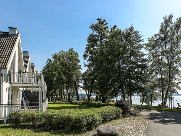 A modern building with a balcony, a paved pathway, and a lake view.