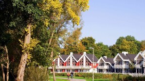 A row of white and red buildings with balconies, surrounded by trees and a pathway. - Nice apartment in villa for 6 people with hot tub, internet, TV, terrace and pets allowed (Fürstenwalde)