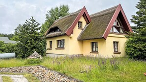 Kaksikerroksinen talo, jossa on olkikatto ja keltainen julkisivu.