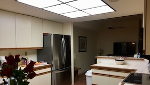 Eine moderne Küche mit weißen Schränken, einem Edelstahlkühlschrank, einer gefliesten Spritzschutzleiste und einer Arbeitsplatte mit Schüssel und Glas.