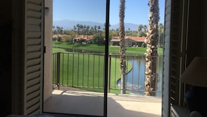 Ein Balkon mit Blick auf einen Golfplatz, Palmen und ein Gebirge.