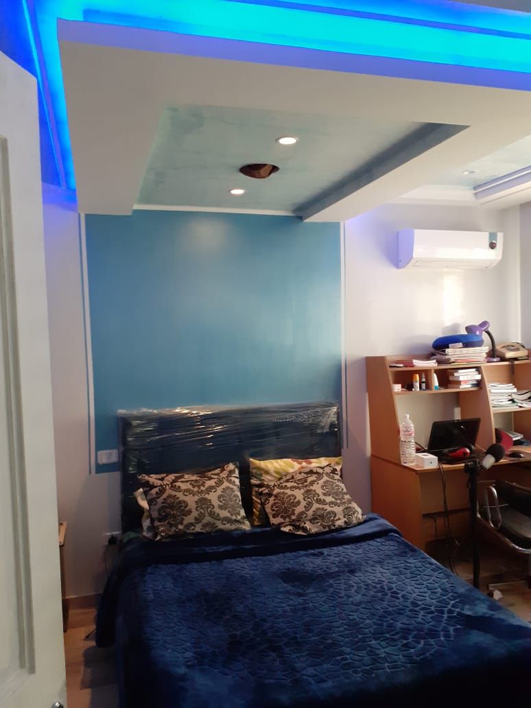 A bedroom with a bed, a desk, and a chair.