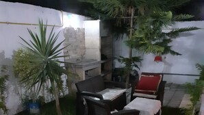 A patio area with outdoor furniture, a small table, and a decorative rug. - The Chedy Home (Ariana)