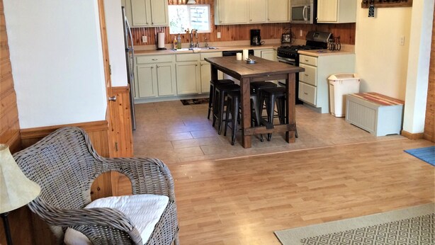 A kitchen with wooden cabinets, a central island with stools, a microwave, and a stove. - Hillside Cottage in Beautiful Downtown Hermann (Hermann)