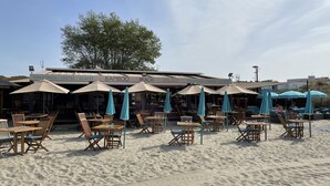 Een restaurant aan het strand met terras en parasols.