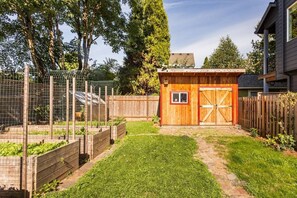 A backyard with a wooden shed, a fenced garden area, and a stone pathway.