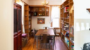 Een eethoek met een houten tafel en stoelen, omringd door boekenkasten vol boeken en decoratieve objecten.