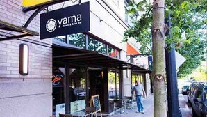 Een sushi restaurant genaamd 'yama' met terras en een zichtbaar menubord.