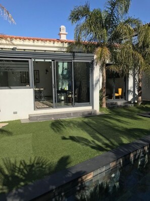 Una casa moderna con puerta de entrada de vidrio, un patio y un césped bien cuidado.