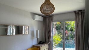 A modern bedroom with a bed, a chair, a dresser, and a large window with curtains.
