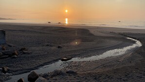 Ein Strand mit ruhiger See, blauem Himmel und Sonnenuntergang oder Sonnenaufgang.