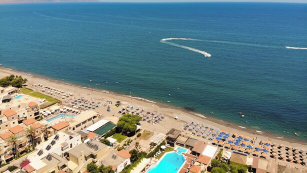 Un hotel frente al mar con varias piscinas, sombrillas y tumbonas.