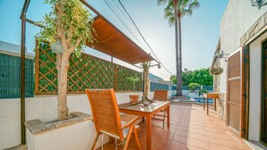 Une terrasse avec une table et des chaises en bois, un petit arbre et un sol carrelé.