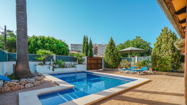 Une piscine rectangulaire dont les bords sont recouverts de carreaux, entourée d’une terrasse en pierre.