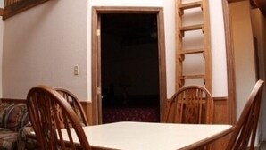 Ein Essbereich mit Holztisch und -stühlen, Deckenventilator und freiliegenden Holzbalken.
