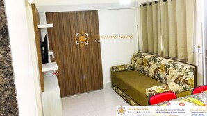 A hotel room with a sofa, a wooden wardrobe, a ceiling fan, and a window with curtains. - Lacqua di Roma Hotel with Water Park and Flats complete with Kitchen (Caldas Novas)