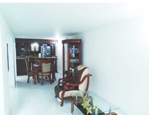 Cozy living space with a dining area and kitchen, featuring a dining table and chairs, a coffee table, and kitchen cabinet.