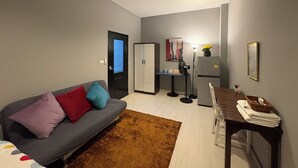 Un espace de vie compact comprenant un canapé, une table à manger, un réfrigérateur et un meuble de rangement.