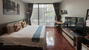 Une chambre d’hôtel moderne dotée d’un grand lit, d’un bureau, d’une télévision et offrant une vue sur l’extérieur.