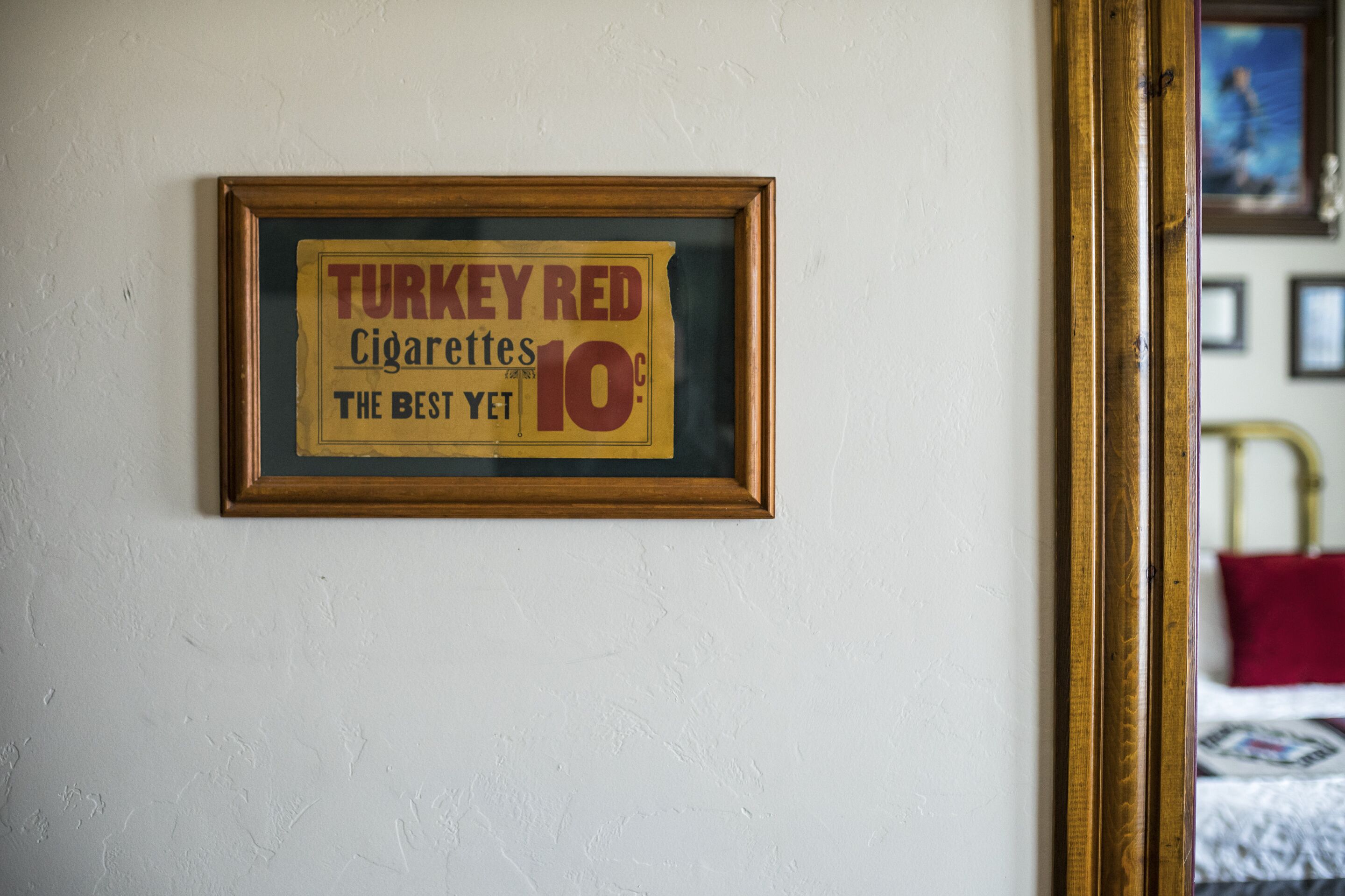 A framed sign on a wall advertising 'Turkey Red Cigarettes' at 10 cents.
