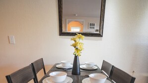 A dining table with four chairs, a vase with yellow flowers, and white bowls on plates. - 2b-1b nearby beach (Daly City)