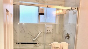 A bathroom with a glass-enclosed shower, a toilet, and a marble-tiled wall. - 2b-1b nearby beach (Daly City)