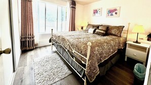 A bedroom with a bed, bedside tables, a window with curtains, and a rug. - 2b-1b nearby beach (Daly City)