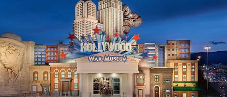 The entrance to the Hollywood Wax Museum with a prominent display of stars and a large building in the background.