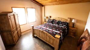 Ein Schlafzimmer mit einem hölzernen Bett, zwei Nachttischen mit Lampen, einem Kleiderschrank und zwei Fenstern.