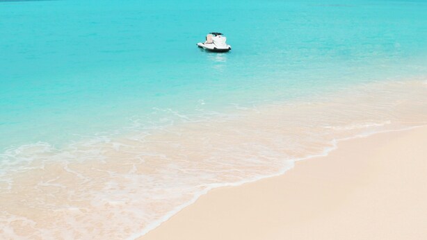 Een jetski op een turquoise strand met zachte golven.