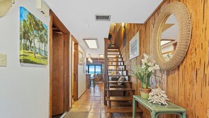 A hallway with a wooden staircase, a green bench, and a mirror on the wall.