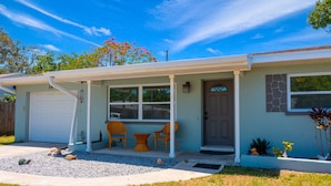 A single-story house with a covered porch, a garage, and a front yard with a gravel area and a small table with chairs.