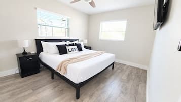 A bedroom with a bed, nightstand, lamp, and a ceiling fan.