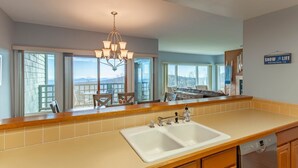 A kitchen with a double sink, wooden cabinets, a chandelier, and large windows overlooking a deck. - WINTERGREEN RESORT HOME WITH BLUE RIDGE VIEWS (Wintergreen Resort)