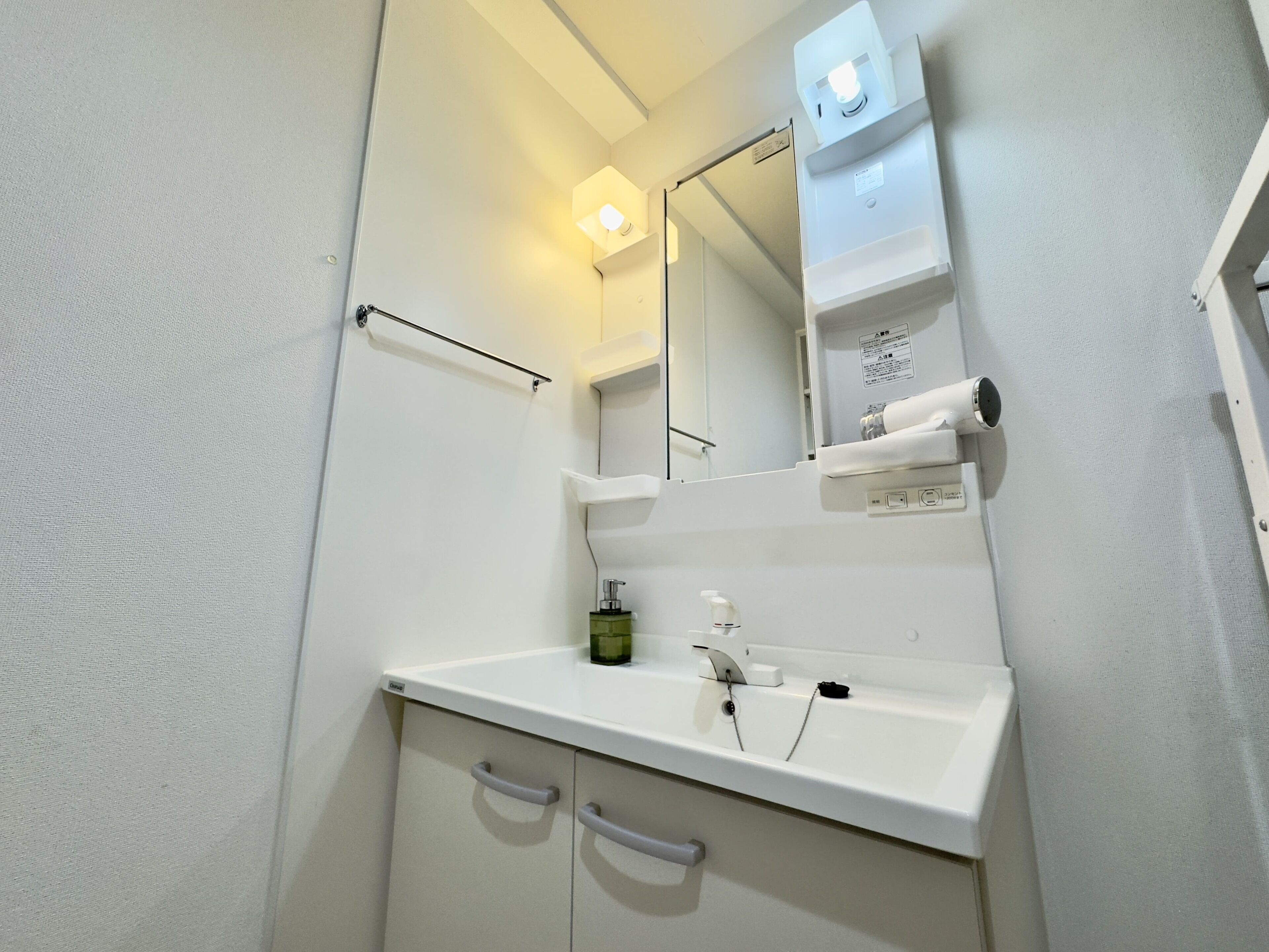 A bathroom with a white sink, mirror, and towel dispenser.
