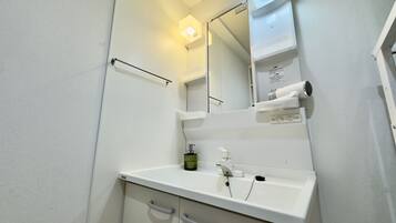 A bathroom with a white sink, mirror, and towel dispenser.