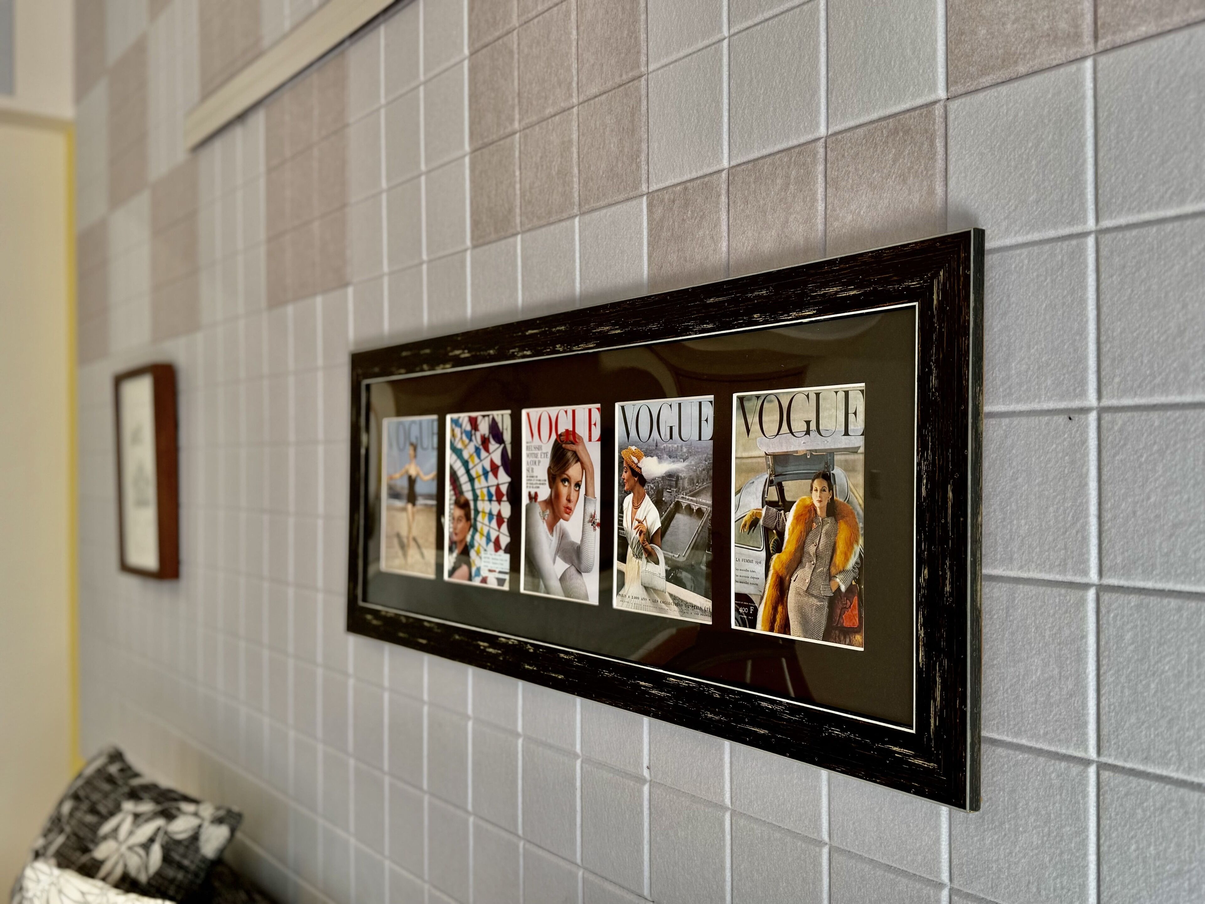 A framed collage of Vogue magazine covers on a tiled wall.