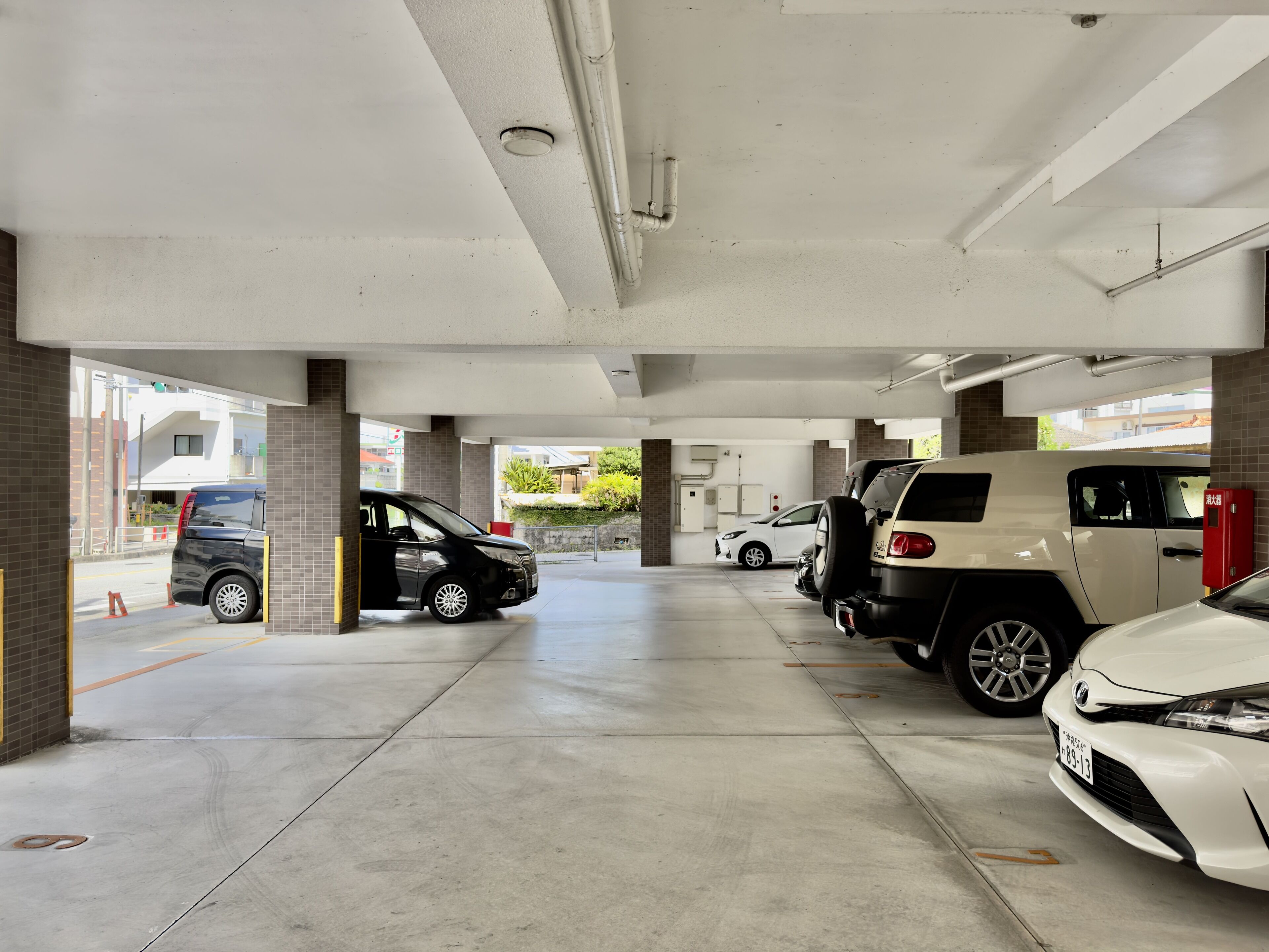 Een parkeergarage met meerdere verdiepingen, betonnen vloeren en enkele geparkeerde auto's.