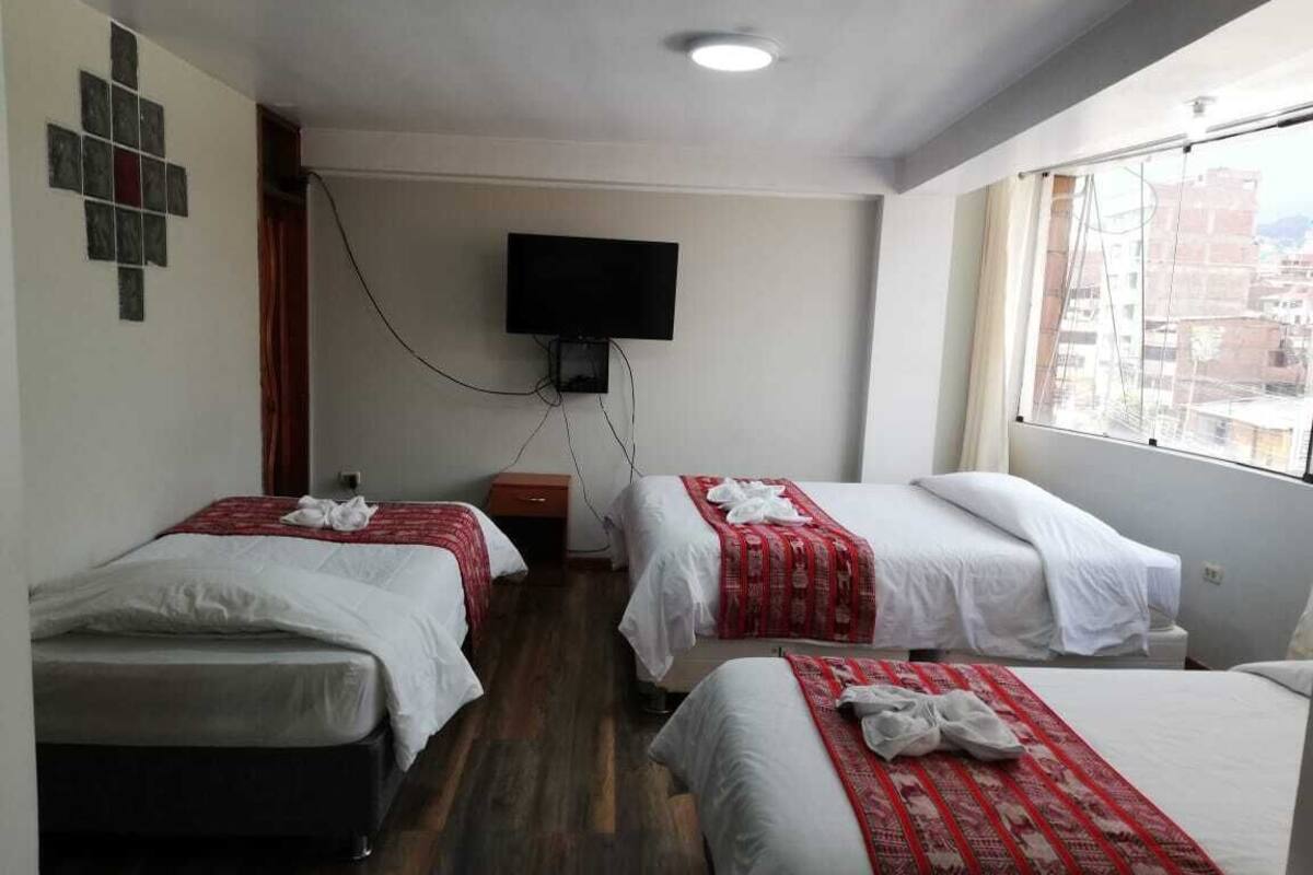 Une chambre d’hôtel avec deux lits, un téléviseur à écran plat fixé au mur et une fenêtre donnant sur la ville.