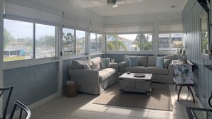 A sunlit room with a ceiling fan, large windows, a sofa, a coffee table, and a chair. - Dolphins, Sunsets & Waterfront Living – Heated Pool + Dock & Kayaks Near Beaches (Englewood)