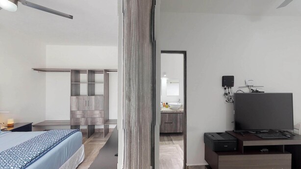 Ein modernes Hotelzimmer mit Bett, Schreibtisch mit Drucker, Flachbildfernseher und Kleiderschrank.