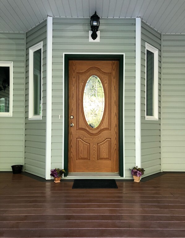 Welcome to a charming home with a beautifully maintained entrance, featuring a decorative glass panel and potted plants.