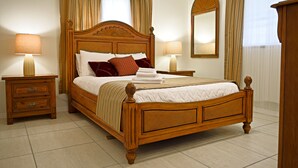 A neatly made bed with a wooden headboard, two bedside tables with lamps, and a large mirror on the wall. - Home in North Port, AC, Wi-Fi, five minutes walk to Warm Mineral Springs  (North Port)